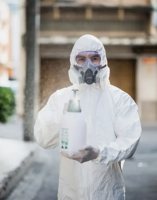 Disinfection specialist man in personal protective equipment (ppe) suit, gloves, mask and face shield, cleaning Quarantine area with a bottle of pressurized spray disinfectant to remove coronavirus